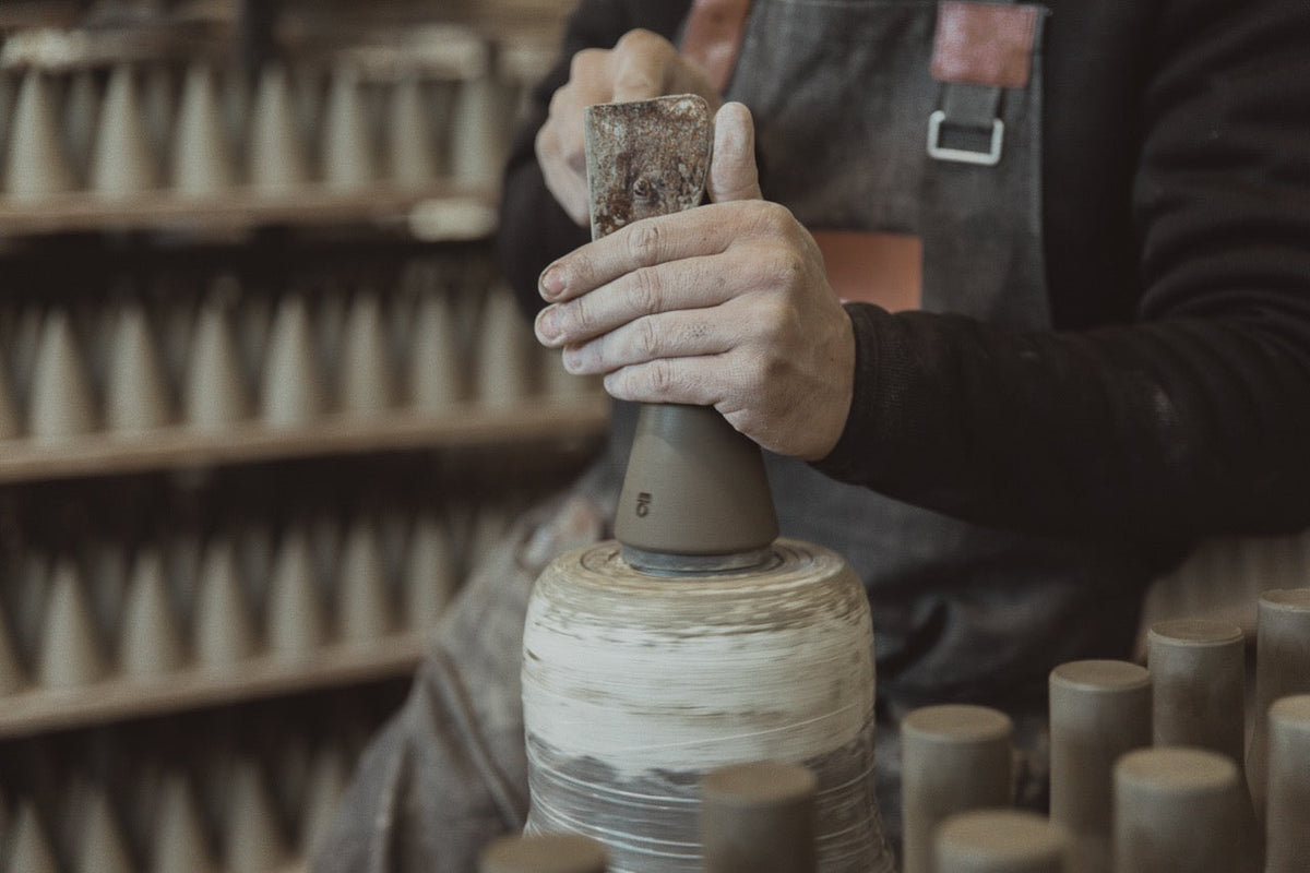 Hands at work at Artigiano, among rows of terracotta pieces