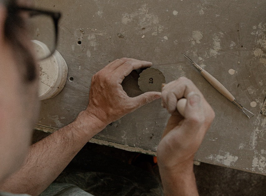 Hands working clay with a modelling tool at Artigiano